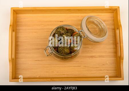 Eine Kugel Blumentee in einem Glasbecher auf einem Holztablett auf weißem Hintergrund. Nahaufnahme Stockfoto