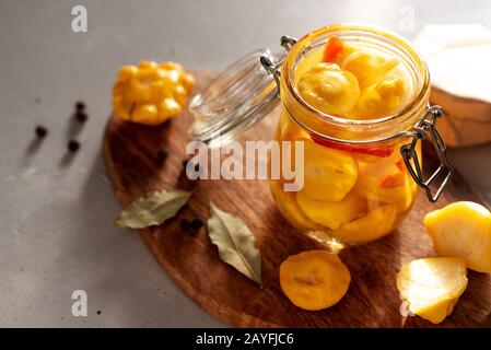 Fermentiertes gelbes Squash-Gemüse in einem Glasbecher. Das Konzept der Konserven. Knoblauch im Vordergrund Stockfoto