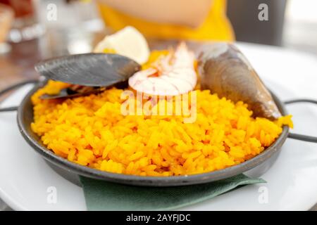 Köstliche spanische Meeresfrüchte Paella in traditioneller Pfanne auf dem Tisch im Café Stockfoto