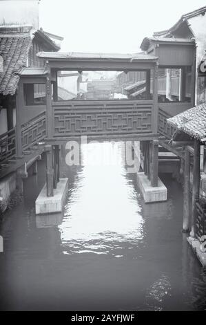 Eine kleine überdachte chinesische Brücke in der historischen wasserstadt wuzhen in der provinz zhejiang in schwarz-weiß. Stockfoto