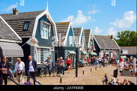 Traditionelle alte Holzhäuser an der Havenbuurt (Hafenumgebung) und Besichtigungstouristen an einem sonnigen Nachmittag. Marken, Niederlande. Stockfoto