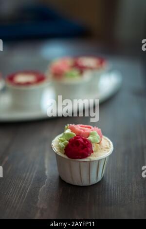Schöne Tassenkuchen Blumen aus Buttercreme, in rot-rosa Farbe. Geeignet für Geburtstag, Jubiläum, Valentinstag und Festtage. Selektive Fokussierung Stockfoto