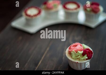 Schöne Tassenkuchen Blumen aus Buttercreme, in rot-rosa Farbe. Geeignet für Geburtstag, Jubiläum, Valentinstag und Festtage. Selektive Fokussierung Stockfoto