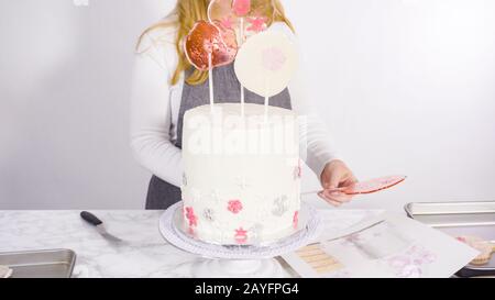 Einfügen von großen Lutscher mit Schneeflocken in den hohen Weiße, runde Kuchen als Dekoration. Stockfoto