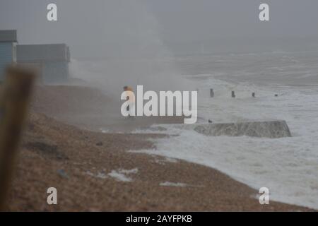 Sturm Dennis, klassifiziert als Bombensturm, bringt Sturmwind und heftigen Regen an die Südküste. Der starke Wind peitscht das Meer in riesige Wellen. Ein Mann am Strand kommt einer großen Welle nahe, Milford-on-Sea, Hampshire, England, Großbritannien, 15. Februar 2020, Wetter: Stockfoto