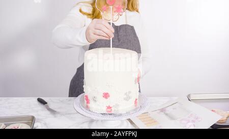 Einfügen von großen Lutscher mit Schneeflocken in den hohen Weiße, runde Kuchen als Dekoration. Stockfoto