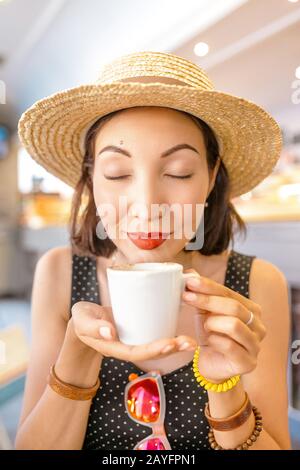 Wunderschönes ostasiatisches Mädchen, das in einem Café Tee oder Kaffee trinkt Stockfoto