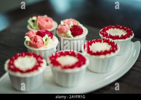 Schöne Tassenkuchen Blumen aus Buttercreme, in rot-rosa Farbe. Geeignet für Geburtstag, Jubiläum, Valentinstag und Festtage. Selektive Fokussierung Stockfoto