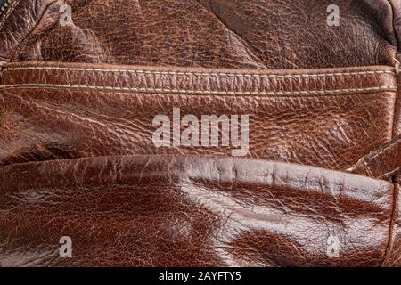 Hintergrundbraunes altes Leder, ein Bruchstück einer schäbigen Tasche, eine stilvolle Sache aus nächster Nähe. Stockfoto