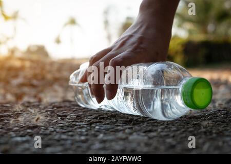 Nahaufnahme Von klarem Wassergetränk aus Plastikflaschen mit einer grünen Kappe auf der Straße im Park auf verschwommenem Hintergrund, Trash, der außerhalb von t liegt Stockfoto