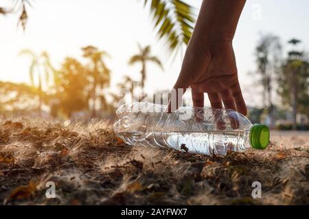 Nahaufnahme Von klarem Wassergetränk aus Plastikflaschen mit einer grünen Kappe auf der Straße im Park auf verschwommenem Hintergrund, Trash, der außerhalb von t liegt Stockfoto
