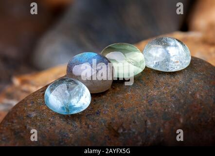 Rund geschnittene Quarz- und smaragdgrüne Mineralsteine mit Steinhintergrund. Stockfoto