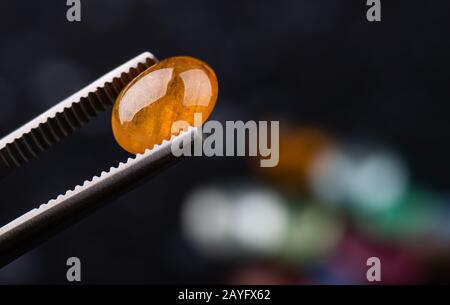 Rund geschnittene orangefarbene Sapphir-Mineralsteine mit dunklem Steinhintergrund. Stockfoto