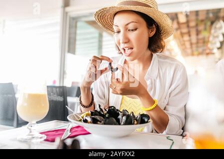 Junge Frau, Die Frisch gekochte Muscheln Isst Stockfoto