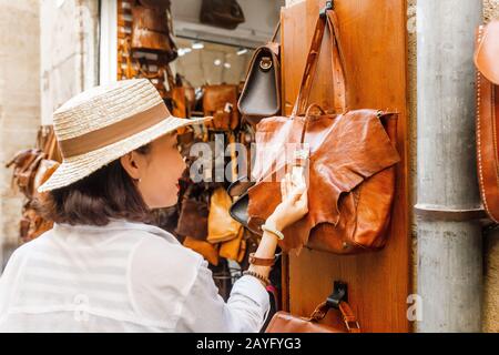 Junge Frau kauft ein und entscheidet sich für eine Tasche im Geschäft Stockfoto