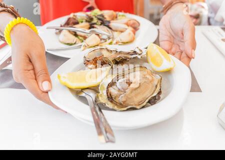 Austern auf dem Teller im Restaurant mit Zitrone Stockfoto