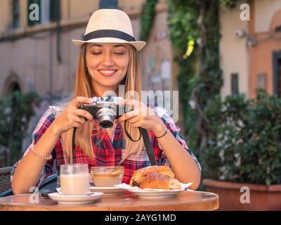 Junge blonde Frau mit blauen Augen, die beim Frühstück in der typischen italienischen Bar im historischen Viertel Trastevere in Rom, Italien, fotografiert Stockfoto