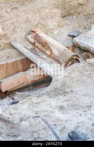 Rostige Kanalisationsrohre - Unterirdisch. Reparatur der Erdwasserversorgung, vertikales Foto. Stockfoto