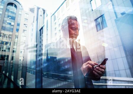 Senioren-Unternehmer organisiert Termine mit dem Handy. Doppelter Belichtungseffekt Stockfoto