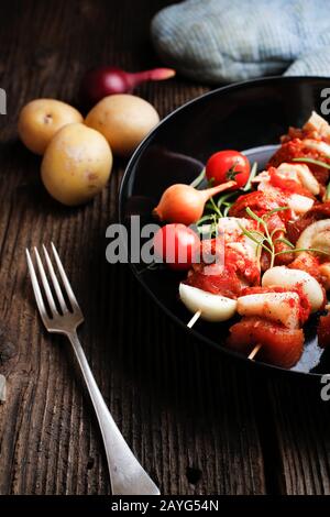 Gemüse und Fleisch auf Holzspießen auf dem Teller. Frittieren Sie das Kebab auf der Bratpfanne. Stockfoto