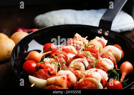 Gemüse und Fleisch auf Holzspießen auf dem Teller. Frittieren Sie das Kebab auf der Bratpfanne. Stockfoto