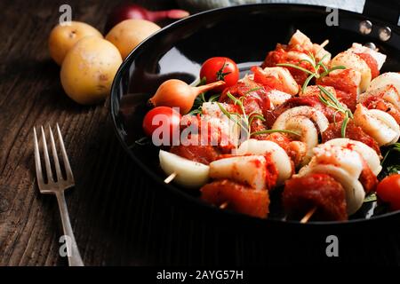 Gemüse und Fleisch auf Holzspießen auf dem Teller. Frittieren Sie das Kebab auf der Bratpfanne. Stockfoto