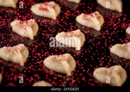 Herzförmige Butter spritzt Plätzchen mit rotem Zucker streut den Fokus auf Herzbokeh Stockfoto