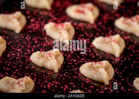 Herzförmige Butter spritzt Plätzchen mit rotem Zucker streut den Fokus auf Herzbokeh Stockfoto