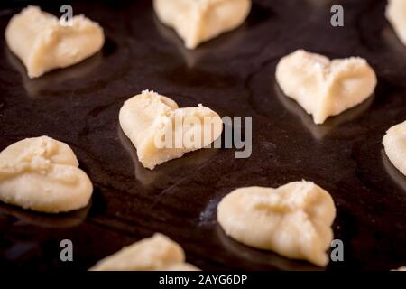 Herzförmige Butter spritzt Plätzchen mit rotem Zucker streut den Fokus auf Herzbokeh Stockfoto