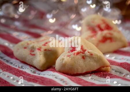 Herzförmige Butter spritzt Plätzchen mit rotem Zucker streut den Fokus auf Herzbokeh Stockfoto