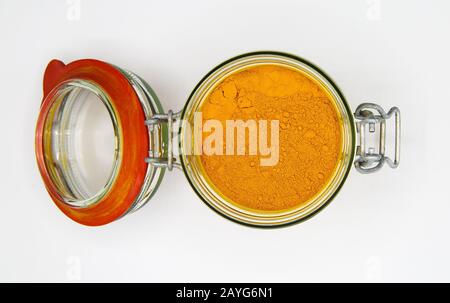 Draufsicht über das Öffnen eines isolierten Konservierungsglaskars mit rotem Gummiring und gelbem Kurkumapulver, weißer leerer Hintergrund Stockfoto