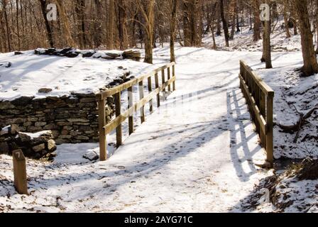 Malerische Aussicht auf eine schneebedeckte Holzbrücke auf einem Wanderweg in einem Park in Great Falls Virginia USA. Stockfoto