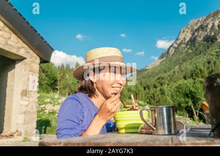 Mädchen, die heißes Essen in der Nähe des Wandercamping-Schutzhauses essen Stockfoto
