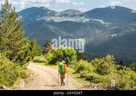 Glückliche Frau, die mit Rucksack in den Bergen der Pyrenäen spazieren geht Stockfoto