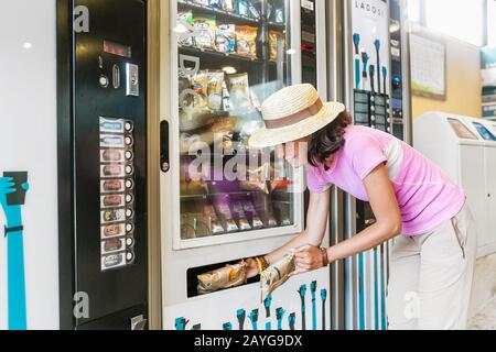 24. JULI 2018, RIBES DE FRESSER, SPANIEN: Frau kauft Chips und andere Snacks vom Automaten Stockfoto