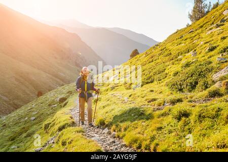 Glückliche Frau, die mit Rucksack in den Bergen der Pyrenäen spazieren geht Stockfoto