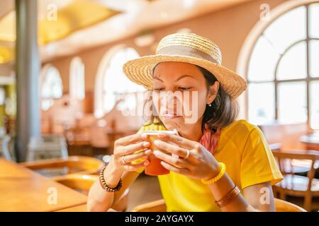 Junge Frau trinkt Kaffee oder Tee aus der Papierbecher im Café Stockfoto