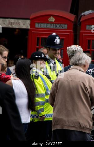 Fröhliche lächelnde Polizisten der Metropolitan, die mit einem Perlkönig in London, England, interagieren Stockfoto