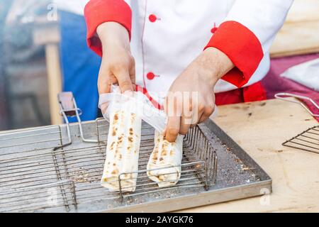Chefhands, die traditionelle Shawarma-Rolle mit Fleisch und Gemüse umhüllen Stockfoto