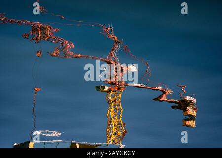 Spiegelung eines Konstruktionsturmkrans auf der Oberfläche eines Wasserkörpers. Stockfoto