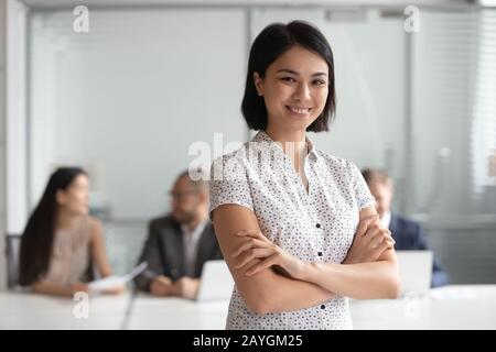 Lächelnde, biraciale weibliche Angestellte, die sich im Büro für ein Bild ausstellen Stockfoto