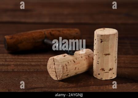 Nahaufnahme von zwei Weinkorken und antiken Korkenziehern auf einem dunklen Holztisch. Stockfoto