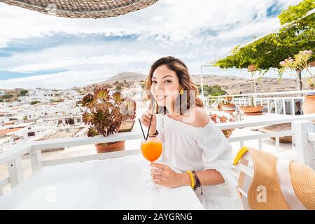 Glückliche asiatin, die aperol Spritz-Cocktail in einem griechischen Café genießen. Getränke- und Erfrischungskonzept Stockfoto