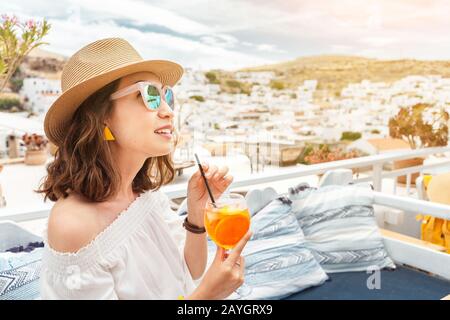 Glückliche asiatin, die aperol Spritz-Cocktail in einem griechischen Café genießen. Getränke- und Erfrischungskonzept Stockfoto