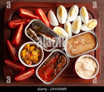 Festliche Platte mit Konserven, Thunfisch, Tomaten, gekochten Eiern, Chutney und Sauce Stockfoto