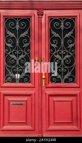 Leuchtende und auffällige rot verzierte Türöffnung. Romantisch dekorierte Messingdetails an dunklen Fenstern und goldenen Details. Aufnahme bei hellem Tageslicht Stockfoto