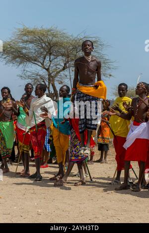 Eine Gruppe junger Samburu-Männer, die in traditioneller Kleidung gekleidet sind und einen traditionellen Springtanz in einem Dorf in Samburu in der Nähe des Samburu National Reserve ausführen Stockfoto