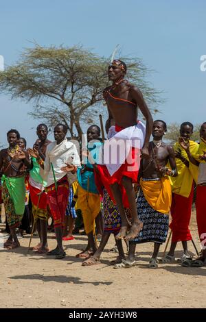 Eine Gruppe junger Samburu-Männer, die in traditioneller Kleidung gekleidet sind und einen traditionellen Springtanz in einem Dorf in Samburu in der Nähe des Samburu National Reserve ausführen Stockfoto