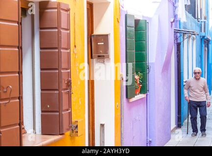 Burano, ITALIEN - 2. MAI 2019: Touristen auf der Straße der alten Bunten Stadt Burano am 2. Mai 2019 auf der Insel Burano in Italien. Blick auf Bunte Häuser. Stockfoto