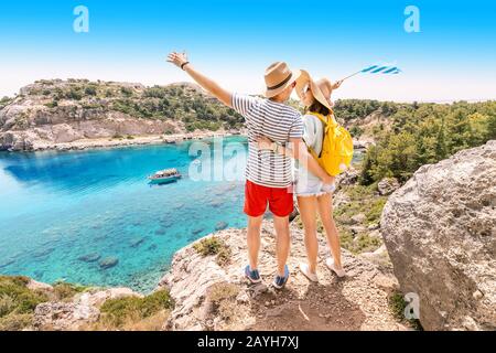 Glückliches Paar liebt es, Urlaub zu machen und auf dem Hügel mit Blick auf die attraktive blaue Meeresbucht zu stehen. Stockfoto